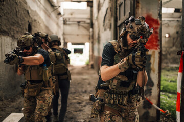 Few extreme friends playing air soft war simulation game in ruins.