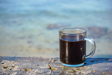 a cup of coffee with a view of the beach in the morning