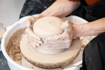 Close-up of a potter's hands working on a pottery wheel. 