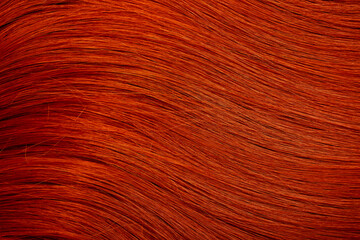 Red hair close-up as a background. Women's long orange hair. Beautifully styled wavy shiny curls....