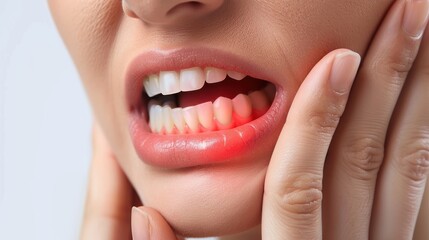 Obraz premium The woman is in pain and discomfort from toothache. She is holding her cheek with her hand and has her mouth open. Her teeth are clenched and her gums are red and inflamed.