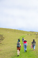 group of people walking uphill in the field, New Zealand