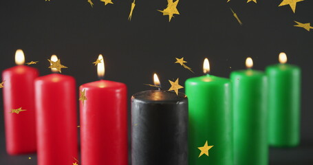 Obraz premium Image of golden stars over kwanzaa candles on black background