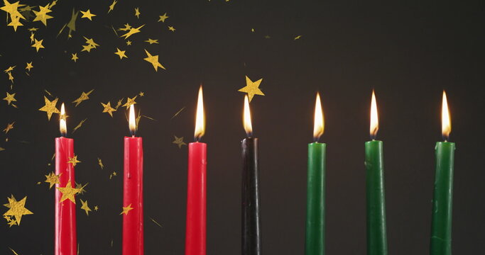 Naklejki Image of golden stars falling over kwanzaa candles on black background