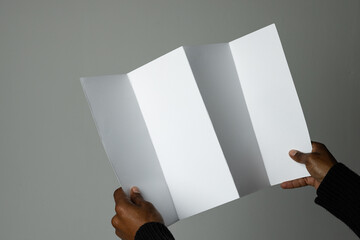 Hands of an African American man holding a blank brochure, with copy space