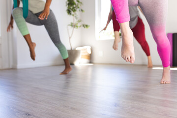 Low section of diverse teenage girls training with female coach at aerial yoga class