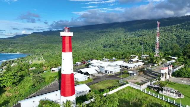 Red and white lighthouse on the Indonesian border, Papua New Guinea, there are mountains and beautiful blue sky clouds