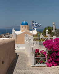 A small traditional Greek church with a blue dome and beige walls under a clear blue sky Santorini...