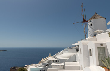 View of traditional white Greek architecture with a windmill on a sunny day against a clear blue...