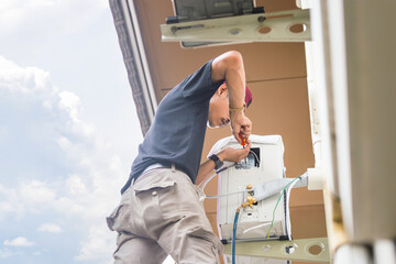 Young repairman fixing air conditioner unit, Asian technician man installing an air conditioning in a client house, Maintenance and repairing concepts