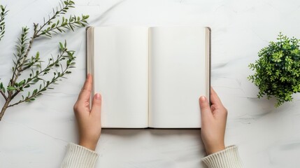 A blank square hardcover book being held on a white background