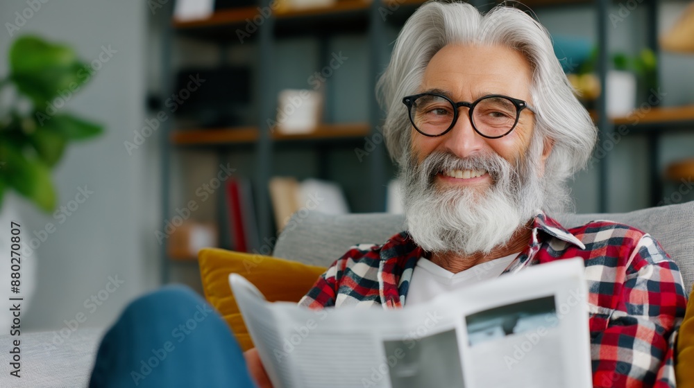 Poster a man with a beard and glasses is sitting on a couch reading a newspaper. he is smiling and he is en