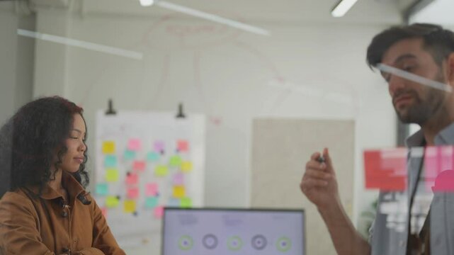 team of developers are currently discussing the feasibility of the project. By writing and pasting work on the glass. Dynamic brainstorming session with a focused team using a transparent idea board.