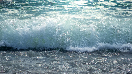Pebble stones, sea water on beach shore close up, selective focus. Seashore with waves and pebbles.