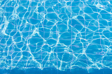 Blue swimming pool water surface and ripple wave background. Summer abstract reflection caustics in swimming pool.