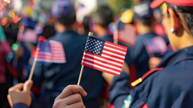 Close-up of hand holding small American flag during a patriotic event.
