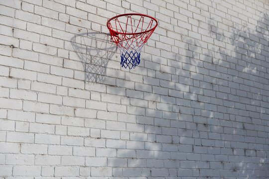 Urban Basketball hoop against white brick wall with a shadow
