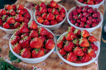 A table with four white bowls full of strawberries