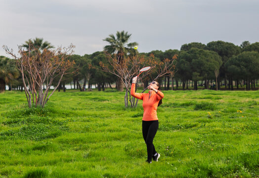 young woman playing badminton on green grass and fprest background