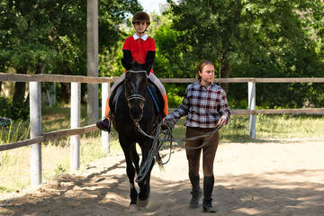 Naklejka premium Young rider follows instructor's lead during equestrian lesson.
