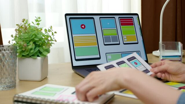Web application designer working on laptop with sketches. Website developer. User experience. Mobile application interface.