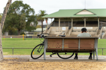park benches and seats in a park around a football sports oval on a sunny spring day, with people...