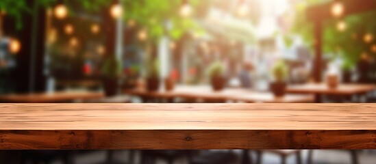 Fototapeta premium The central focus is an empty brown wooden table set against a blurred Coffee shop background with bokeh effect for showcasing products in a copy space image.