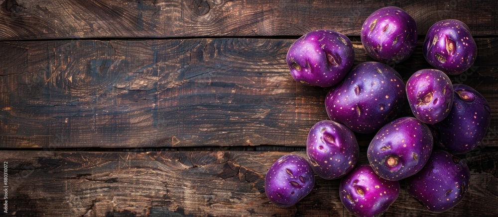 Poster top view of vibrant purple potatoes on rustic wood surface with ample copy space image.