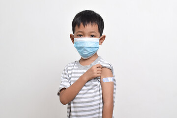 Asian boy using face mask with plaster bandage on his arm after vaccination. Vaccine injection. Child immunization. Health services for children. copy space