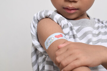 Asian boy with plaster bandage on his arm after vaccination. Vaccine injection. Health services for children. copy space