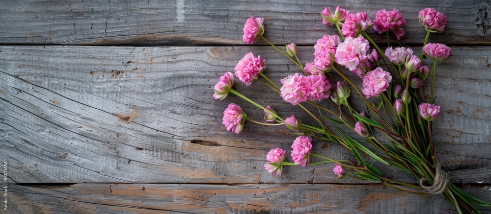 Poster Bouquet of pink cloves flowers for spring arranged on a rustic wooden surface from above for a flat lay photo with copy space image.