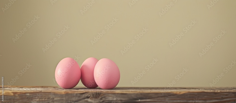 Poster pink easter eggs displayed on a wooden table, set against a neutral beige backdrop, with ample space
