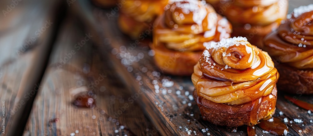 Poster close-up horizontal image of homemade pumpkin cinnabons drizzled with cane sugar caramel on a dark w