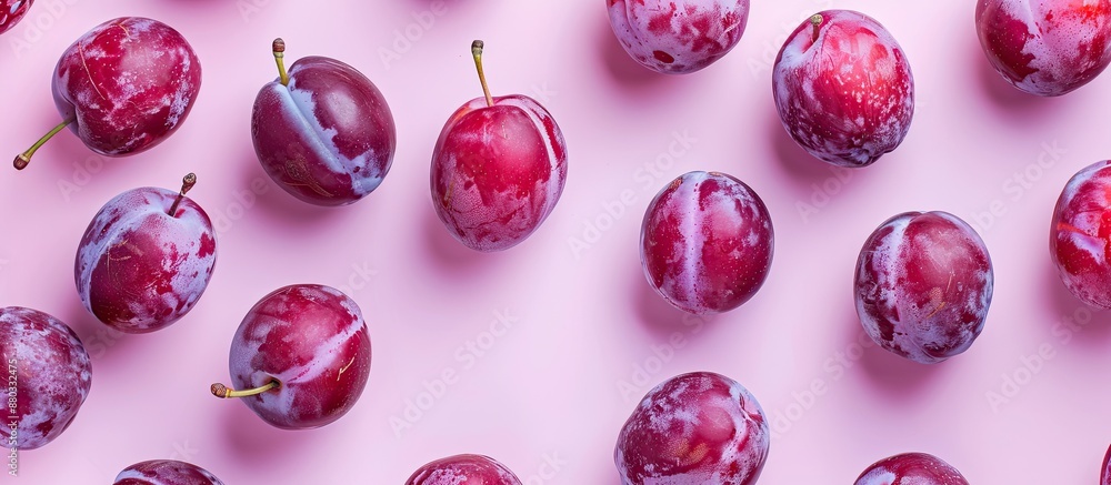 Poster Plump ripe plums scattered on a soft pink background with gentle lighting creating a captivating copy space image