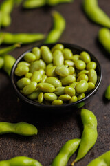 Green edamame pods. Fresh soybeans in bowl on black table.
