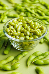 Green edamame pods. Fresh soybeans in bowl on green table.