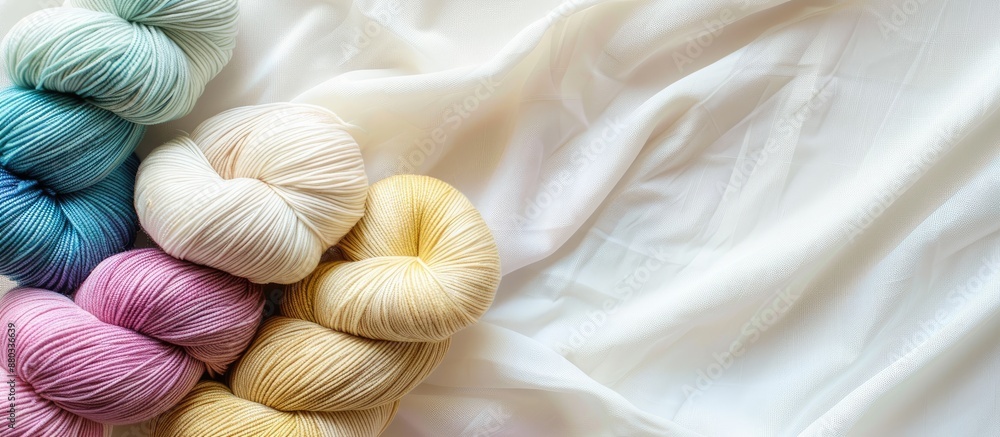 Poster white cotton jersey fabric background with a spool of raw organic cotton yarn in various colors crea