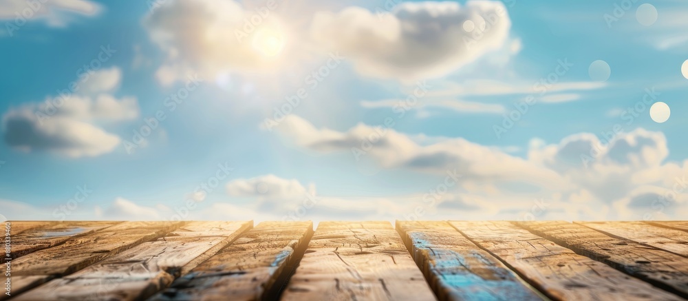 Poster focused on an empty brown wooden table against a blurred blue sky background with bokeh effects perf