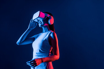 Smart female stand with surrounded by cyberpunk neon light wear VR headset connecting metaverse,...