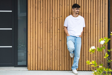 Front view of a fashionable young man standing against the wall