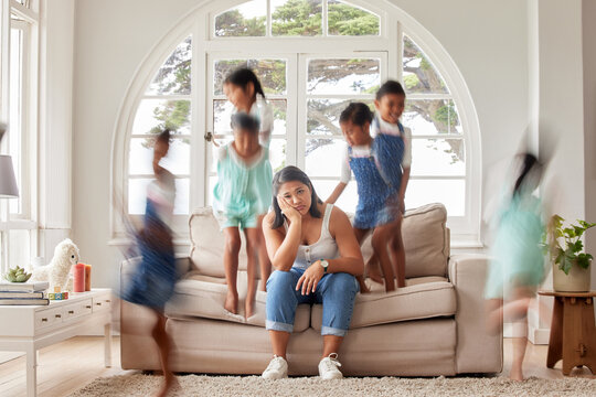 Stress, tired and portrait of single mother with kids playing on couch with exhausted mom or composite. Headache, frustrated and overwhelmed parent with adhd children jumping on sofa in family home