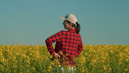 Woman In A T-Shirt Standing In A Flowering Canola Rapeseed Field. Pretty Young Woman With Arms Raised In Air In Rapeseed Field.