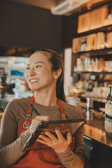 Happy Asian Waitress working with digital tablet in the restaurant 