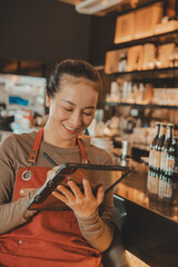 Happy Asian Waitress working with digital tablet in the restaurant 