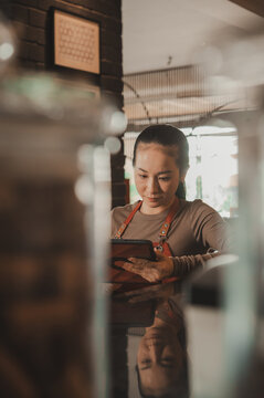 Happy Asian Waitress working with digital tablet in the restaurant 