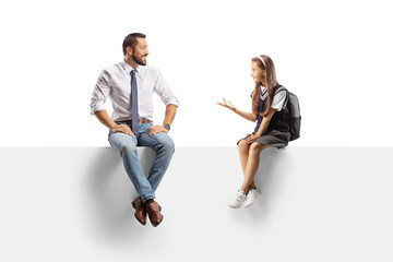 Fototapeta premium Schoolgirl sitting on a panel and talking to a man