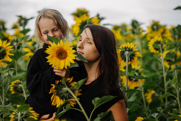 Naklejka premium Mother and daughter happy together in a field with sunflowers