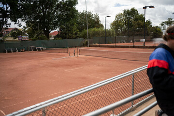 people playing tennis on a clay court at a local tennis club. young attractive people playing social tennis with friends and people watching enjoying being active and healthy