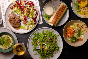 Table scene of assorted take out or delivery foods. Hamburgers, pizza, fried chicken and sides. Top down view on a dark wood banner background.