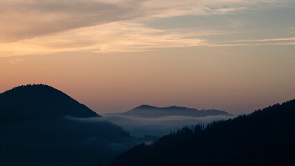 Sunset above horizon line with sun setting down behind mountains